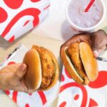 chick-fil-A sandwiches held up by hands with the company logo beneath them