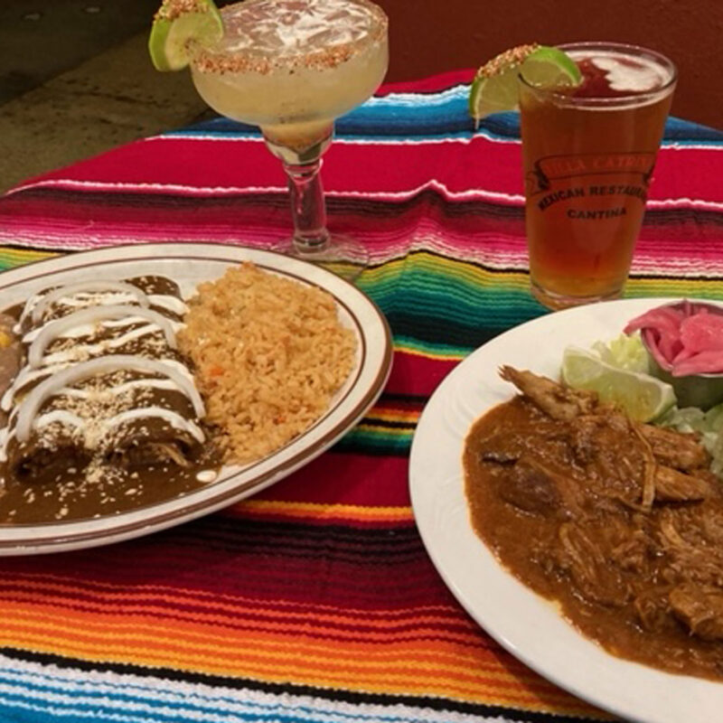 Both Chicken Mole Enchiladas and Cochinta Pible on plates with drinks from Villa Catrina