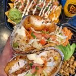 a Baja Cali fish burrito showing fish, rice, guacamole, cheese and tomatoes with lettuce