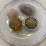 items of dim sum situated on a white plate with a silver rim